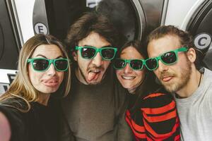 group of young friends wearing green sunglasses having fun taking a selfie photo