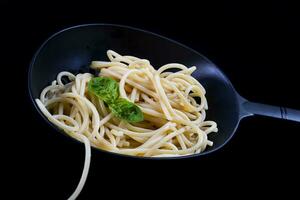 Italian spaghetti with basil leaves cooked in a colander photo