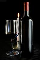 studio composition with red wine bottle and glass and burning candle photo