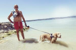 mature man relaxing with his dog in the fresh water photo