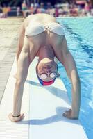 Young adult woman in swimsuit makes gymnastics photo