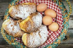 freshly baked croissants and four eggs with powdered sugar in a basket ready for breakfast photo