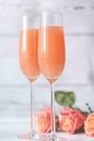 Two glasses of bellini cocktail with bouquet of roses photo