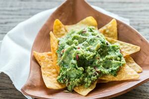 Guacamole with tortilla chips on the wooden background photo