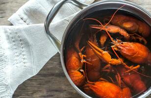 Pot with boiled crayfish on the wooden table photo