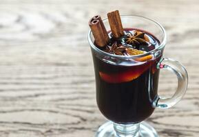 Glass of mulled wine on the wooden background photo