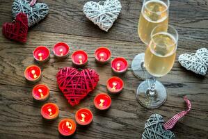 Two glasses of champagne with burning candles and cane hearts photo