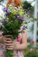 ramo de flores de flores silvestres en el manos de un niña foto