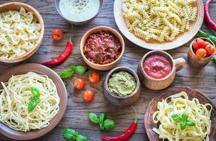 Pasta with different kinds of sauce on the wooden background photo