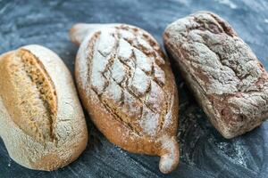 Whole grain breads on the dark wooden background photo