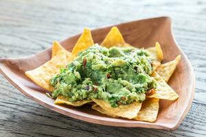 Guacamole with tortilla chips on the wooden background photo