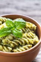 Fusilli with pesto sauce on the wooden background photo