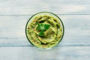 Bowl of guacamole on the wooden table photo