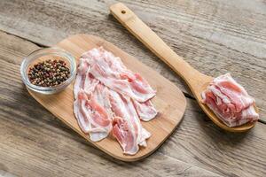 Bacon strips with pepper on wooden board photo