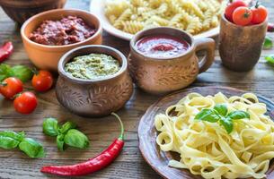 Pasta with different kinds of sauce on the wooden background photo