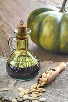 Bottle with pumpkin oil on the wooden background photo