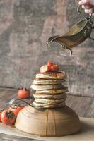 Pancakes with fresh persimmon and maple syrup photo