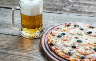 cocido Pizza con un vaso de cerveza foto