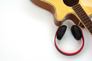 Acoustic guitar on a white background and the headphones are placed on the side. Concept of love, leisure and music. photo