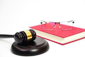 Close up of judge gavel or hammer and blurred glasses on the law book placed behind. Law, judiciary concept. photo