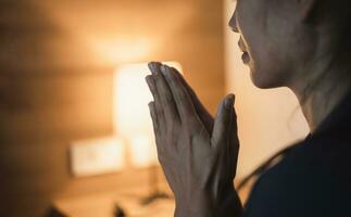 Christian woman praying in bedroom, woman hands praying to god, begging for forgiveness and believe in goodness. Christian life crisis prayer to god. Christian life crisis prayer to god. photo