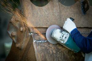 Hands of worker grinding a piece of metal,Grinding steel, Sparks from the grinding wheel. photo