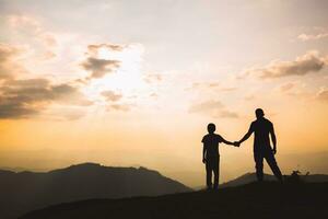 silhouette of family on the outdoor at dusk, happy family relax on the mountain. photo