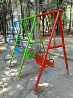 Back view of swing in the garden, empty swings in the playground, colorful swings in the park photo