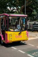 Jakarta, Indonesia - October 2 2023. Bright Pink and Yellow Jakarta Bus photo