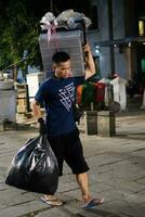 Jakarta, Indonesia - October 2 2023. Man Carrying Heavy Loads Across Street photo