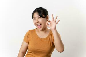 The cheerful young Asian woman smiling and showing the OK hand sign standing on white background. photo