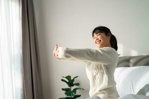 Happy Woman stretching her arms on the bed in the morning. photo