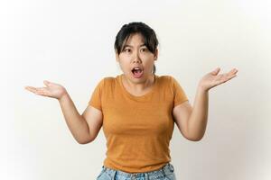 The confused beautiful Asian woman shrugging shoulders spreads hands sideways standing on white background. bewilderment, doubting, have no idea, don't know. photo