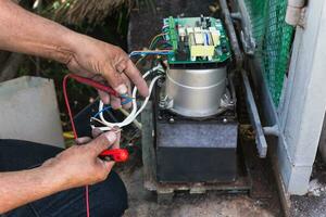 manos de un electricista con multímetro Investigacion a eléctrico tablero panel. foto