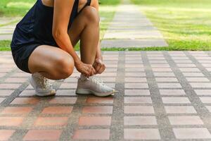 Woman fitness runner tying shoe laces getting ready for jogging outdoors. photo