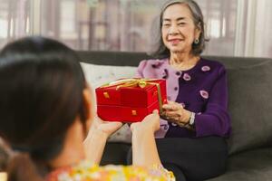 Daughter giving gift box to mother at home. photo