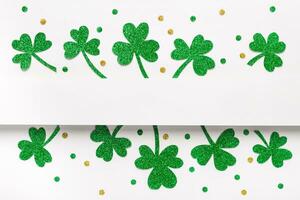 Happy St. Patricks Day minimal background. Green glitter shamrocks border on white background photo