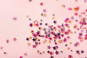 Multicolor holographic Stars Glitter Confetti on pink background. Festive backdrop, selective focus photo