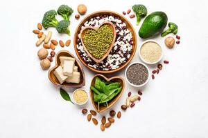 Sources of vegetable protein laid out in the shape of a heart on a white background photo