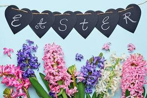 Happy easter greeting card. Multicolored hyacinth flowers and garland with Easter word. Easter concept. Flat lay photo