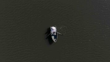 aéreo Visão barco com noivas em a fundo do a fabuloso brilho do a sol, que é refletido dentro a água do uma ampla lago. video