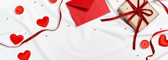 Romantic concept. Valentines day banner. Red envelope, Gift box and hearts on white silk sheet photo