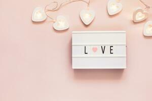 Minimal Valentine flat lay with word love on lightboard and garland. Love concept. Valentine's day, copy space photo