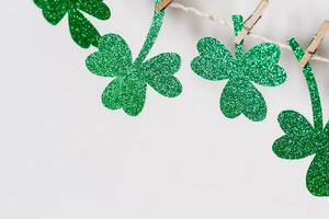 Happy St. Patricks Day background. Green glitter shamrocks homemade garland, copy space photo