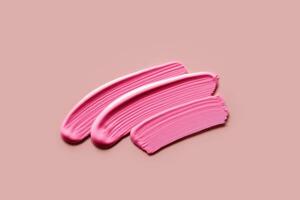 Pink eye shadows or liquid lipstick Samples on pink background. Swatches of cream makeup strokes photo