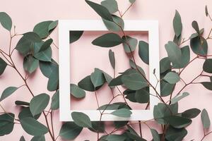 Natural creative background. Eucalyptus branches and white square frame on pink background. Minimal summer concept photo