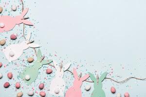 Easter background with diy paper rabbits garland and sweet easter eggs photo
