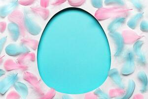 Blue easter Egg shaped hole with copy space. Creative layout with colored feathers pattern. Happy easter concept, greeting card photo