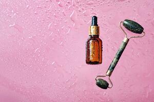orgánico productos cosméticos y jade masaje rodillo. protección de la piel producto botella y agua gotas en rosado antecedentes foto