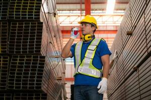 Warehouse workers in hard hats and helmets stand in the warehouse to count and inspect the steel in the warehouse. photo